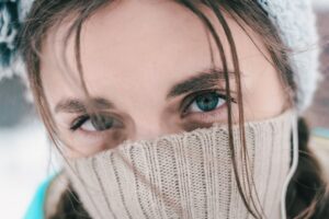 woman with brown hair covering her face with white knit textile